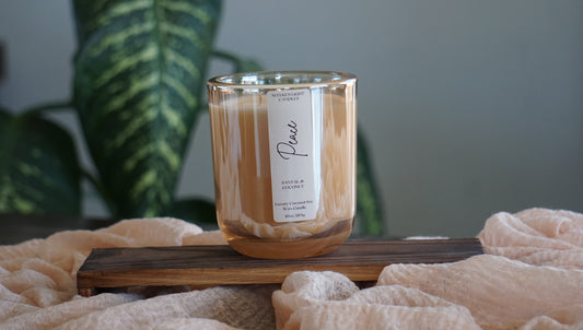 Candle with a label on a wooden stand in front of a plant