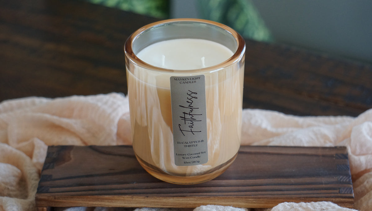 Candle labeled 'Faithfulness' on a wooden coaster with a soft background