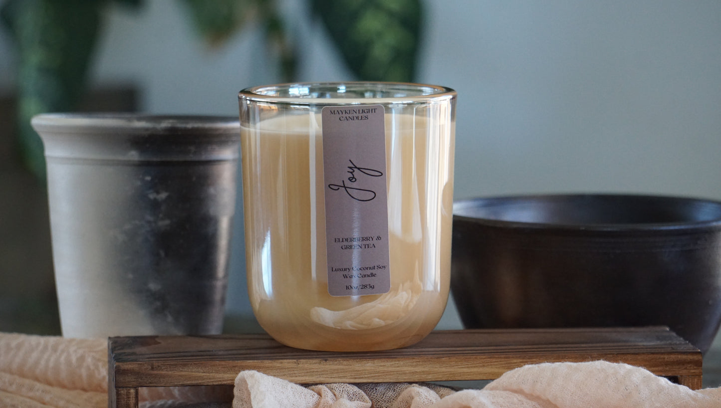 Candle with a label on a wooden surface, surrounded by decorative items.