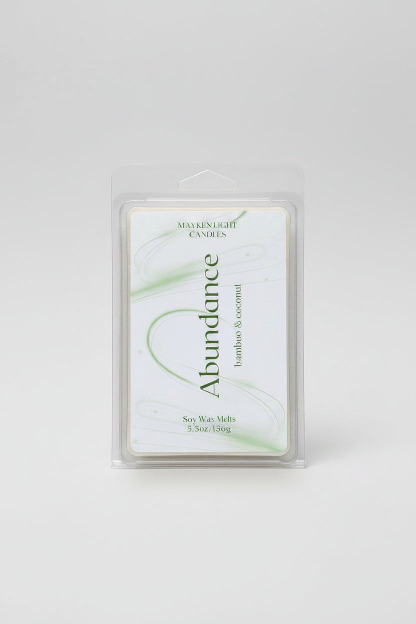 clear container with a white and green label for Abundance. Scents of Bamboo and coconut. 5.5 oz/156g