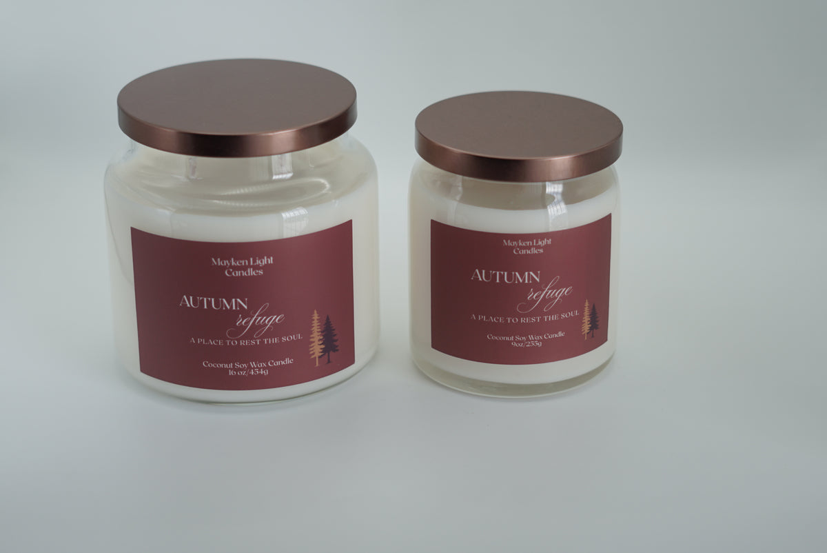 Two glass jar candles with metallic rose gold lids and maroon labels, displayed side by side on a light gray background.