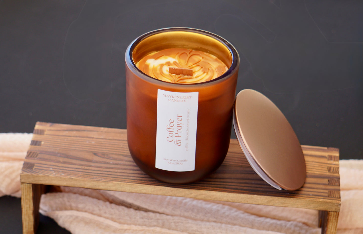 Candle with a label on a wooden stand against a dark background