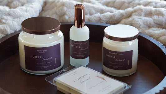 Picture is a 16 oz candle, 9 oz candle, wax melt and room spray with the name Faithful harvest on a burgundy label on round wooden tray and a fluffy blanket in the background. 