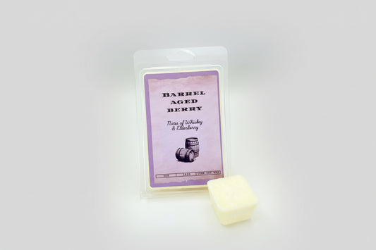 Packaged wax melts with a label reading 'Barrel Aged Berry', featuring an image of a whiskey barrel and elderberry, indicating a fragrance note of whiskey & elderberry.