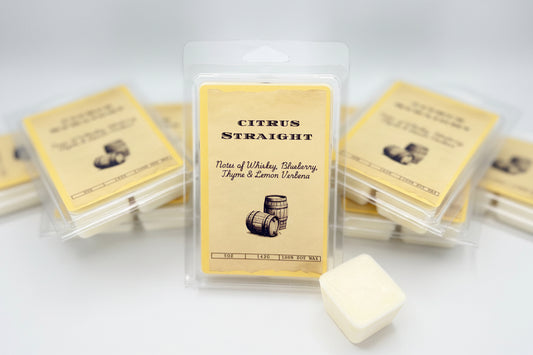 Packaged wax melts with a label reading 'Citrus Straight', mentioning scent notes of whiskey, blueberry, thyme, and lemon verbena.