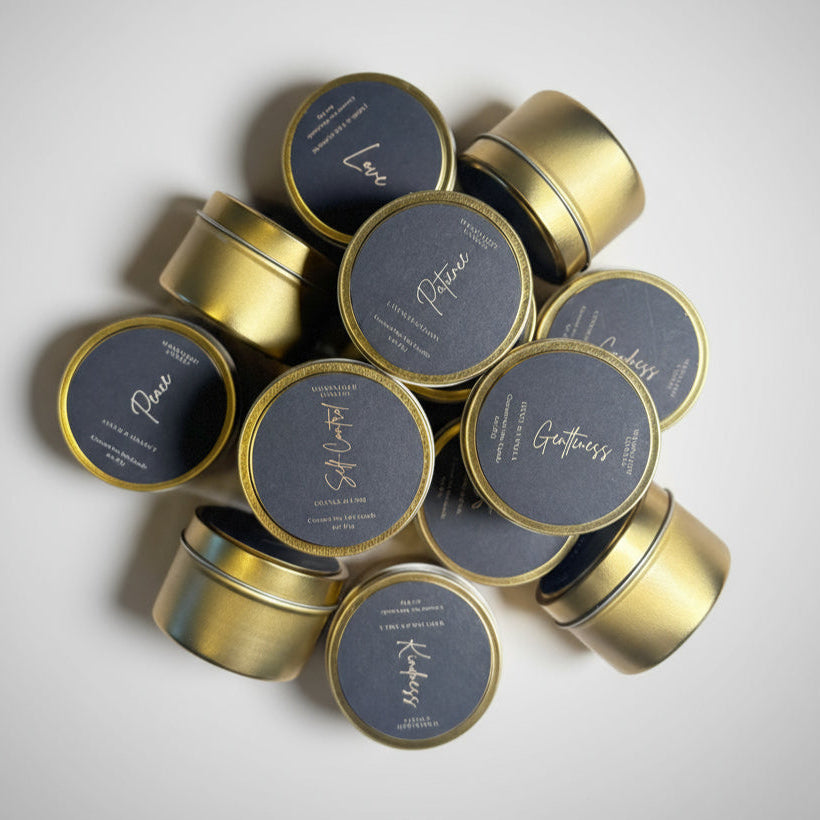 Gold tins with black abels on a textured white surface