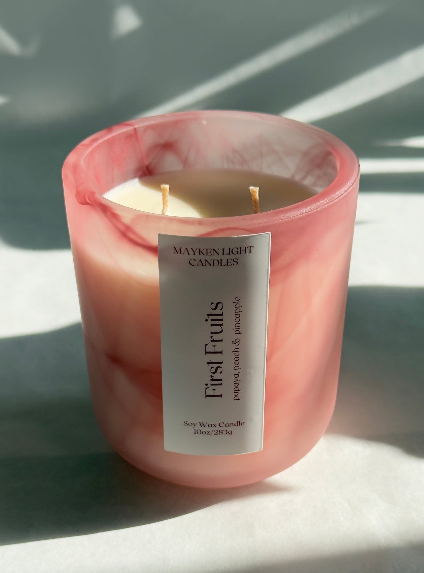 Pink candle with a label on a light surface