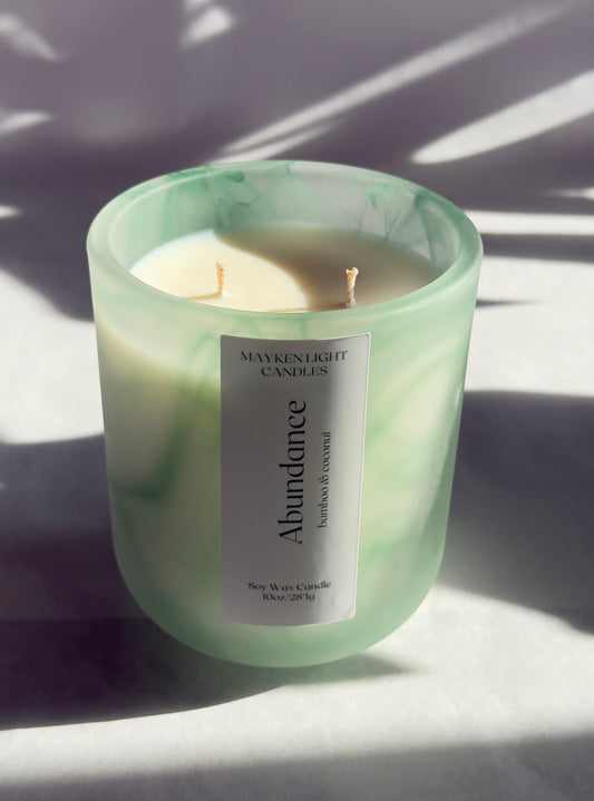 Green candle with a label on a light surface