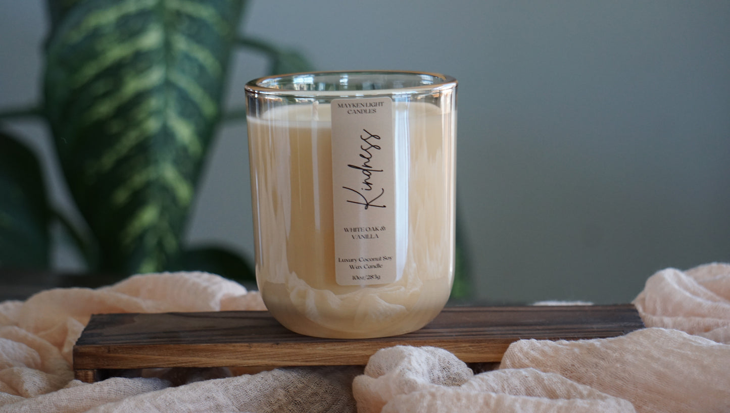 Candle with a label on a wooden tray against a blurred green background