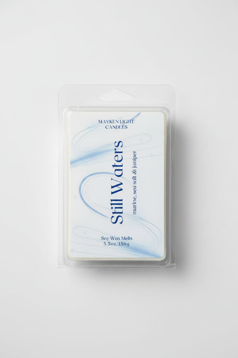 Clear container with white and blue label for Still Waters. Scent of Marine, Sea Salt, and Juniper. 5.5 oz/156g