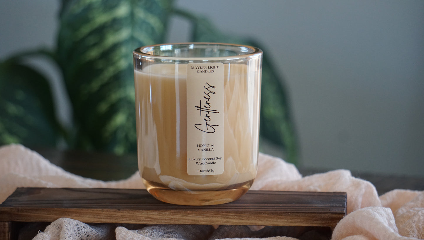 Glass candle with wooden lid on a wooden stand, blurred green plant in the background