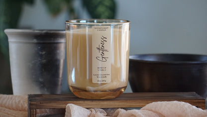Glass candle with a label on a wooden surface, with a blurred background