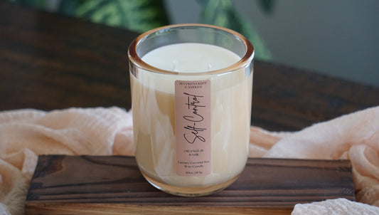 Candle in a glass jar on a wooden surface with a soft focus background