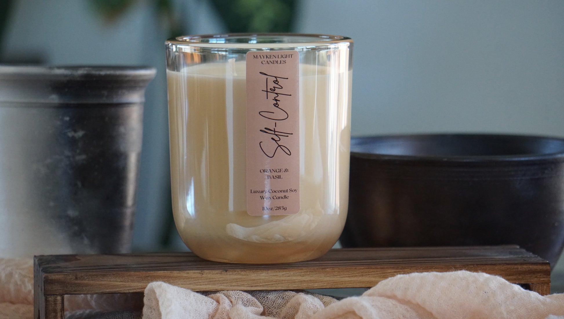 Glass candle with a label on a wooden surface, blurred background
