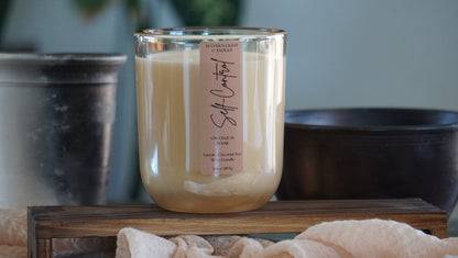 Glass candle with a label on a wooden surface, blurred background